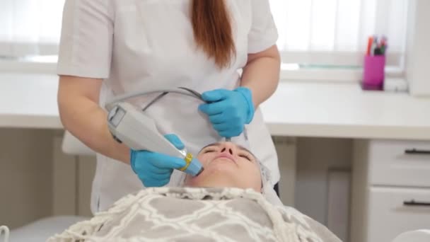 Женщина-косметолог делает лазерное омоложение лица. — стоковое видео