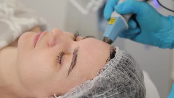 Mujer cosmetóloga trata a los clientes cara con láser. — Vídeos de Stock