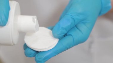 Kadın güzellik uzmanı yüzünü temizlemek için pamuk yastığını ıslatıyor..