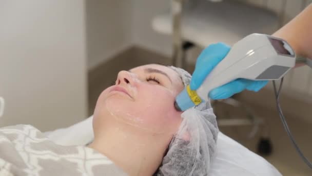 La esteticista trata su cara con un láser. Rejuvenecimiento facial . — Vídeos de Stock