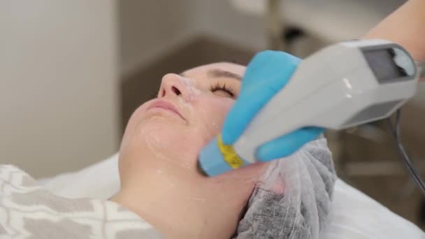 Kobieta kosmetyczka traktuje swoją twarz laserem. Odmładzanie twarzy . — Wideo stockowe