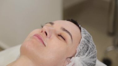 Kadın güzellik uzmanı yüzünü pamukla siliyor..