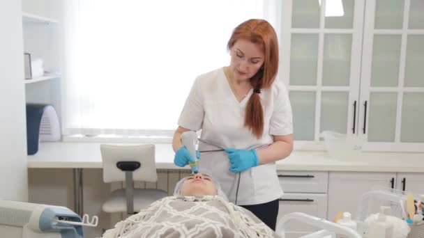 Mujer cosmetóloga trata a los clientes cara con láser. — Vídeo de stock