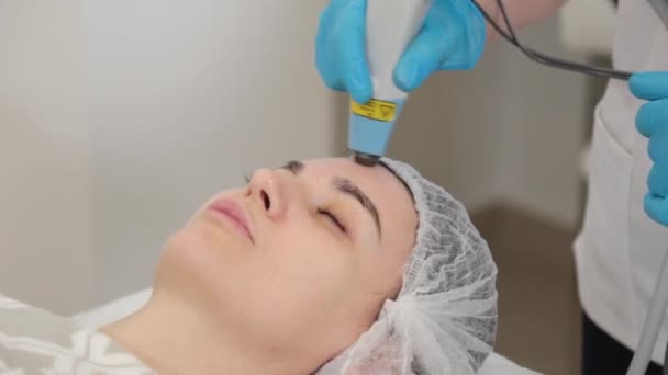 Woman cosmetologist treats clients face with laser. — Stock Video