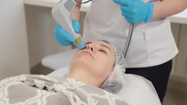 Mujer esteticista haciendo rejuvenecimiento facial con láser. — Vídeo de stock