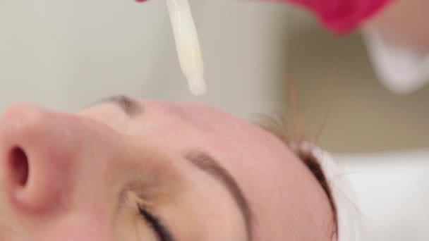 Жінка-косметолог кидає сироватку з піпеткою на її обличчя . — стокове відео