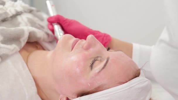 Donna cosmetologa tratta il suo viso con un dispositivo in ufficio cosmetologia. — Video Stock