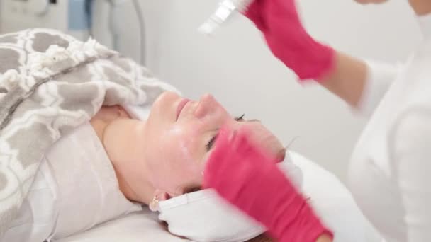 Donna cosmetologa tratta il suo viso con un dispositivo in ufficio cosmetologia. — Video Stock