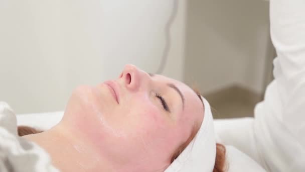 Femme esthéticienne frotte sérum sur le visage des clients. — Video