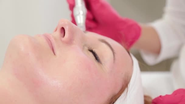 Жінка-косметолог лікує обличчя пристроєм в косметологічному кабінеті . — стокове відео