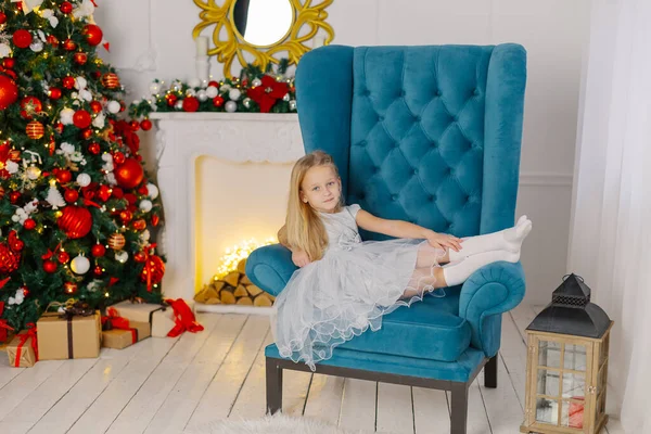 Beautiful little girl sitting on a chair by the tree. Stock Photo