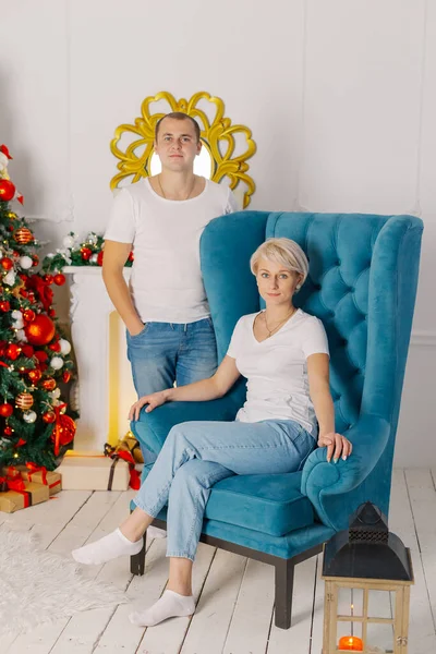 Jeune beau couple au sapin de Noël sur le fauteuil. — Photo