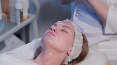 Kadın güzellik uzmanı ıslak mendille kadınların yüzündeki kremi temizliyor..