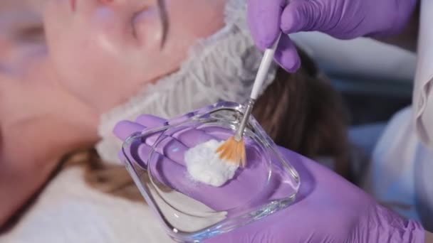 Kvinna kosmetolog omrörning grädde med en borste i en glasbehållare. — Stockvideo