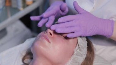 Kadın güzellik uzmanı kadınların yüzüne krem sürüyor..