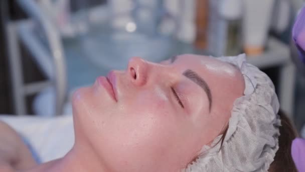 Mujer esteticista aplica suero con cepillo a cara de mujer. — Vídeos de Stock