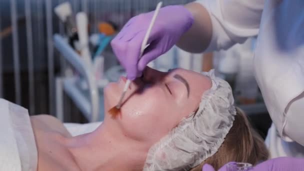 Esthéticienne femme applique du sérum avec brosse sur le visage de la femme. — Video