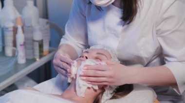 Güzellik uzmanı kadın güzellik muayenehanesinde bir kadının yüzünü siliyor..