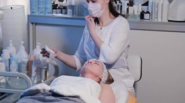 Güzellik uzmanı kadın güzellik muayenehanesinde bir kadının yüzünü siliyor..