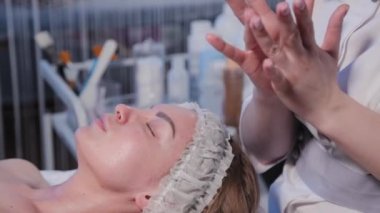 Kadın kozmetik uzmanı kadın yüzüne makyaj kremi sürüyor..