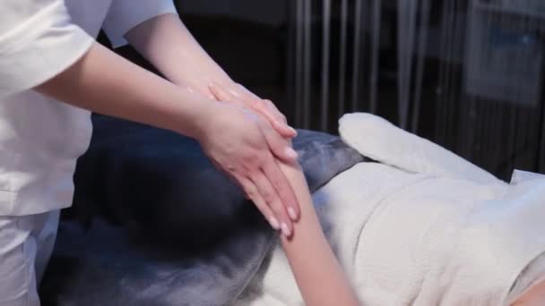 Mulher cosmetologista fazendo massagem de mão para mulher no procedimento de cosmetologia. — Vídeo de Stock