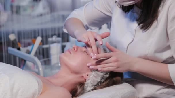 Il cosmetologo di donna applica la crema cosmetica su faccia di donna. — Video Stock