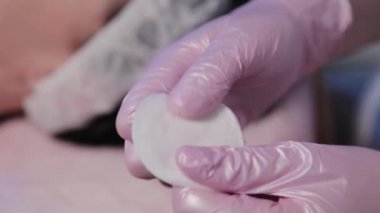 Güzellik uzmanı kadın yüzünü pamukla siliyor..