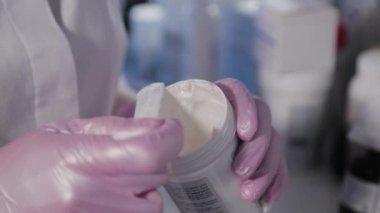 Kadın güzellik uzmanı kavanozlardan krema topluyor..