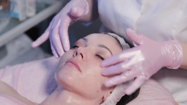 Femme esthéticienne applique crème sur le visage de la femme. — Video