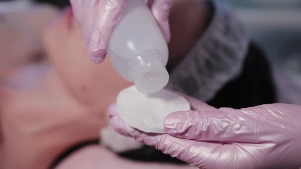 Kvinna kosmetolog fuktar en bomullspad. — Stockvideo