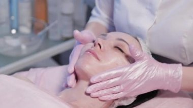 Kadın güzellik uzmanı kadınların yüzüne krem sürüyor..