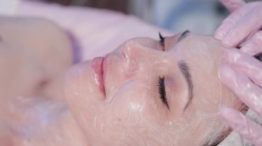 Kadın güzellik uzmanı kadınların yüzüne krem sürüyor..