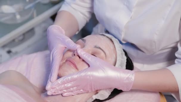 Kobieta kosmetyczka masuje krem na twarz kobiet. — Wideo stockowe