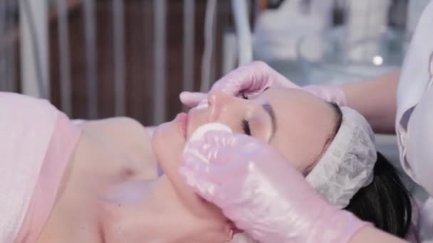 Femme esthéticienne essuie femme visage avec coton pad. — Video