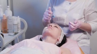 Kadın güzellik uzmanları şırıngayı yüzüne doğru soyar..