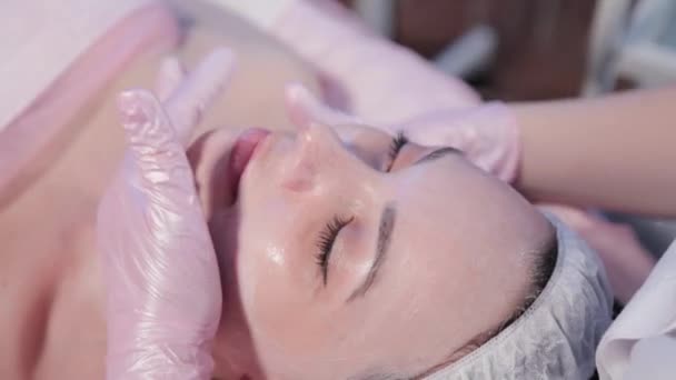 Kvinna kosmetolog gnuggar kvinnor ansikte. — Stockvideo