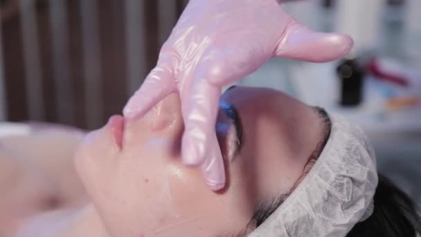 Kobieta kosmetyczka stosuje krem do oczu kobiet. — Wideo stockowe