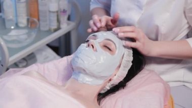 Kadın güzellik uzmanı kadın yüzünün maskesini çıkarıyor..