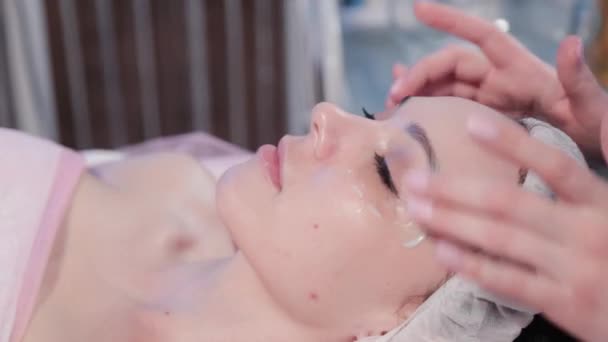 Kobieta kosmetyczka masuje krem na twarz kobiety. — Wideo stockowe