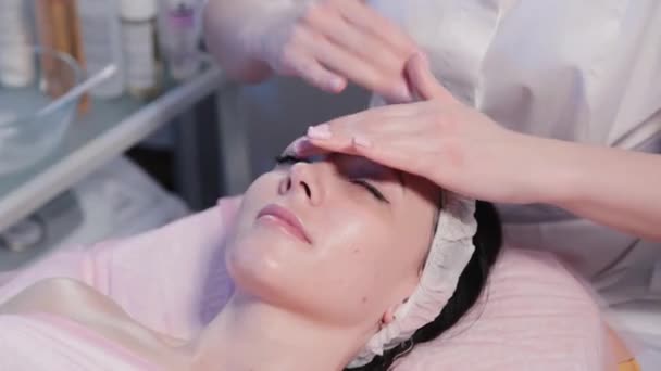Donna estetista strofina la crema sul viso della donna. — Video Stock