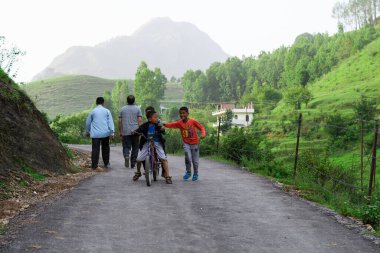 Bazı çocuklar 19 Haziran 2018 'de Pithoragarh, Uttrakhand, Hindistan' da bisikletle şarkı söylüyorlar.