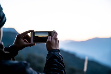 Dağlarda akıllı telefonla fotoğraf çeken bir kadın.