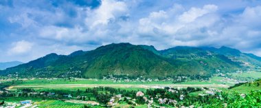 Dağları ve bulutlu gökyüzü olan güzel bir manzara.