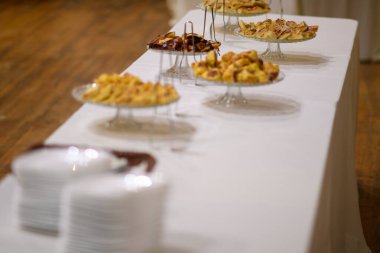 Zarif Açık Büfe. Baharatlı Aperatifler ve Lezzetli Tatlılar Beyaz Masa Örtüsü Üzerinde Kutlama ya da Kutlama İçin Hazırlandı.