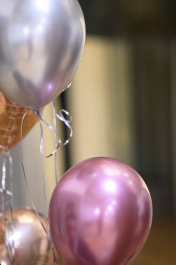Shiny Metallic Balloons in Rose Gold Silver and Purple Floating Upwards Creating a Festive Atmosphere for Celebrations and Parties with Ribbons Attached