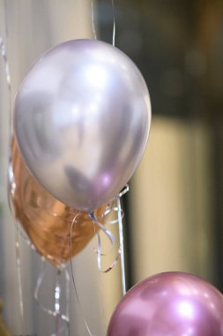 Festive metallic balloons float gracefully in the air creating a celebratory atmosphere for a special event or party occasion with shimmering ribbons.