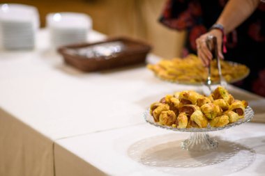 Bir etkinlikte şeffaf bir cam kaidenin içinden servis edilen, altın kahverengisinden yapılmış hamur işi rulolarının yakın çekimi.