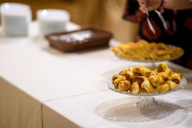 Lezzetli ev yapımı aperatifler ve tatlılar beyaz bir tezgahta sanatsal bir şekilde düzenlenmiş bir parti ya da toplanma için açık büfe hazırlıyorlar.
