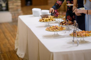 Lezzetli Aperatifler ve Tatlılar Çeşit Çeşnisi içeren Zarif Açık Masa Kurulumu Resmi Toplantı veya Kutlama Etkinliğinde Konukların Konuk Standı 'nda sergilendi