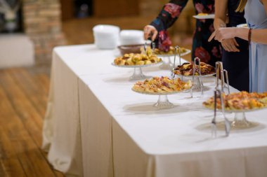 Şık bir açık büfe masası. Lezzetli aperatifler ve tatlılar. Kutlama için konuklar toplanıyor.